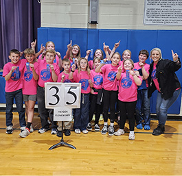 Students and teacher in pink shirts in from of a sign with the number 35 on it